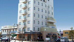 A multi-story hotel with balconies, a ground-level restaurant, and a clear blue sky.