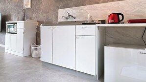 Eine kompakte Küchenzeile mit einer Mikrowelle, einem kleinen Kühlschrank und einer Kaffeemaschine auf der Arbeitsfläche.