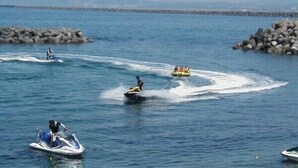 Uma extensão de água com jet skis e um pequeno barco.