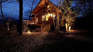 A wooden cabin with a staircase leading to the entrance, surrounded by trees and a clear sky. - Place Yatsugatake Oigamori Cottage (Hokuto)