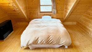 A wooden cabin room with a bed, a window, and a television. - Place Yatsugatake Oigamori Cottage (Hokuto)