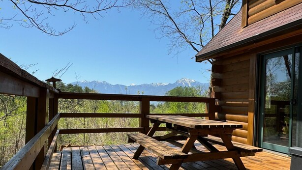A wooden deck with picnic tables overlooking a mountainous landscape. - Place Yatsugatake Oigamori Cottage (Hokuto)