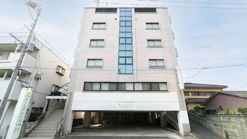 A multi-story hotel with a central elevator shaft, a covered entrance, and a sign indicating it is a hotel.