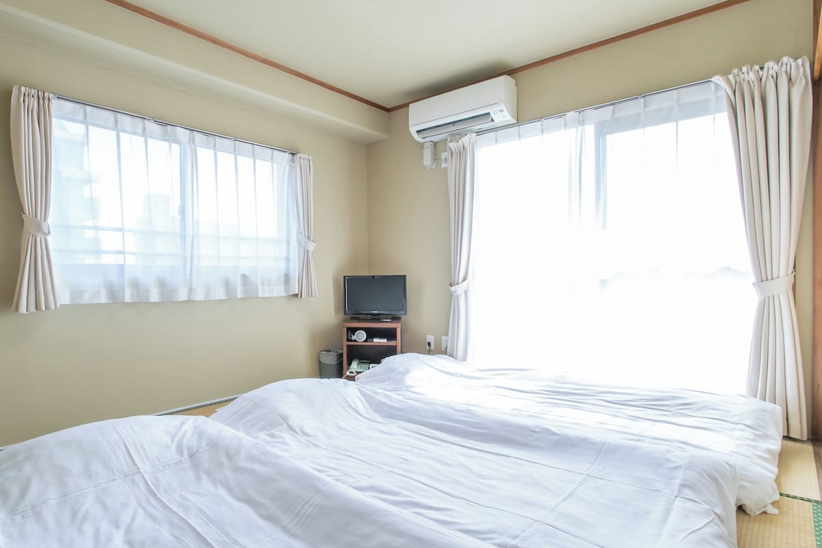 Una habitación de hotel con una cama, televisor y aire acondicionado.
