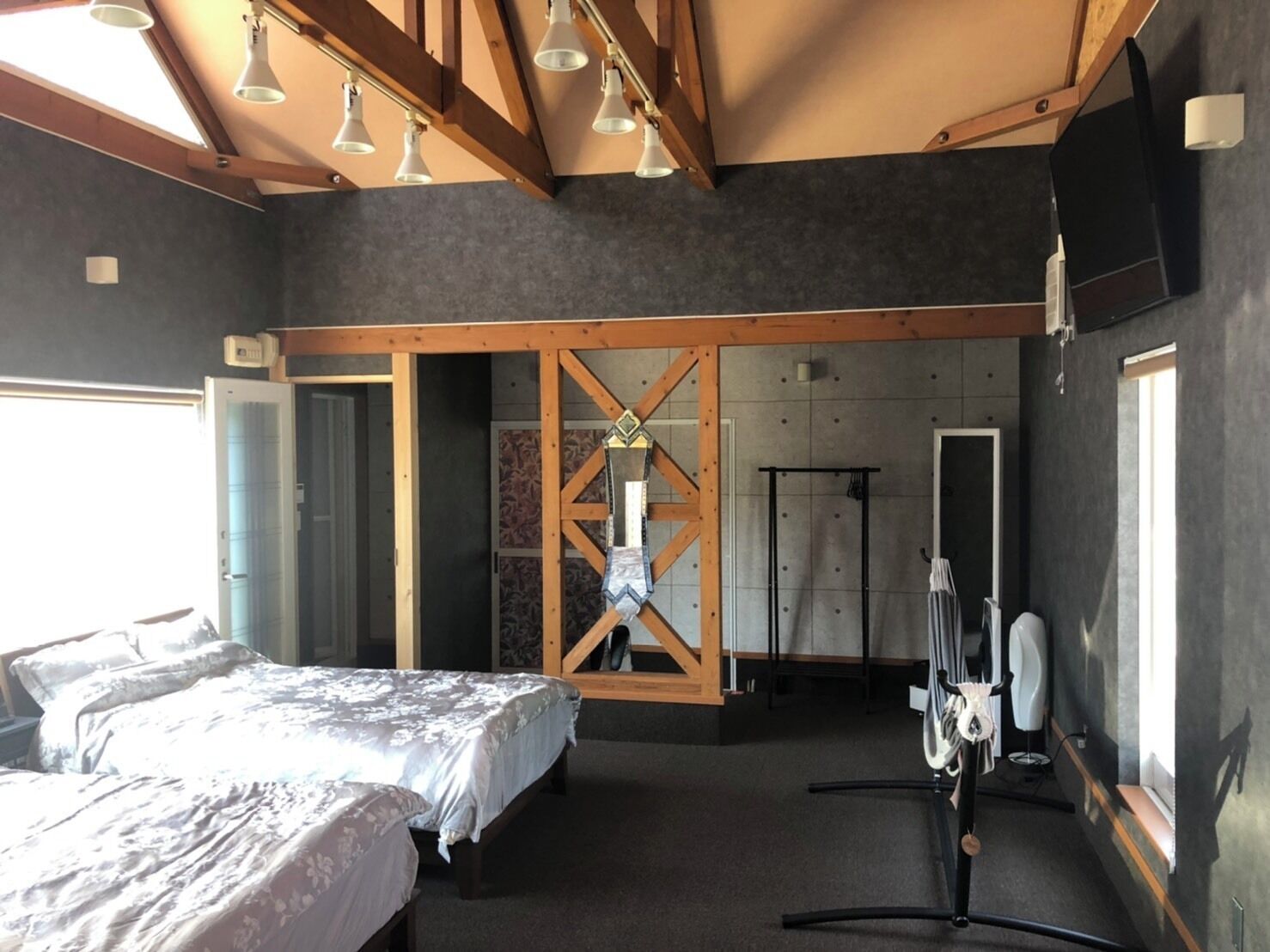 A bedroom with a bed, a wardrobe, a mirror, and a shower area.