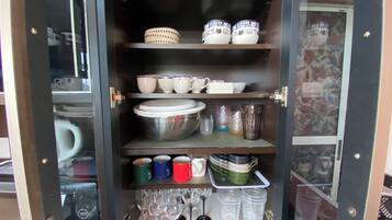Un armario de cocina con estantes que contienen diferentes platos, tazas y vasos.