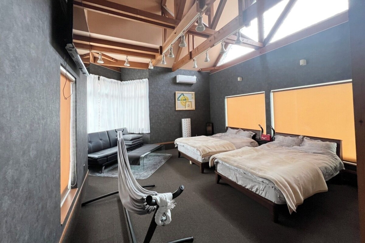 Ein Hotelzimmer mit Bett, Sofa, Hängematte und einem großen Fenster.