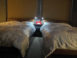 Habitación de hotel con dos camas, una mesita de noche y un objeto rojo sobre ella.