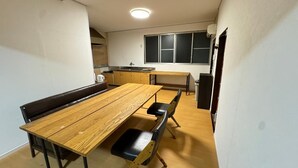 Una cuina compacta amb zona de menjador, taula de fusta i una banca.