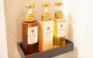 Tres botellas de productos de baño sobre una repisa.