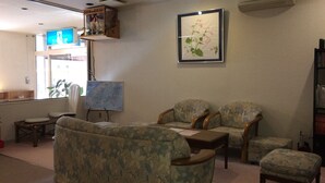 Un salón con muebles de estampado floral, un grabado botánico enmarcado y una pizarra.