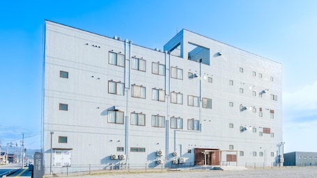 A modern hotel building with a grid-like facade, multiple windows, and a central entrance.