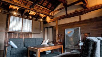 A traditional Japanese room with tatami flooring, a low wooden table, a sofa, and a painting.
