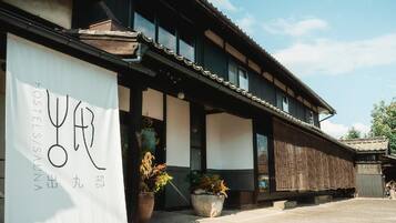 A traditional building with a sign reading 'HOSTELS/SALON' and a large potted plant in front.