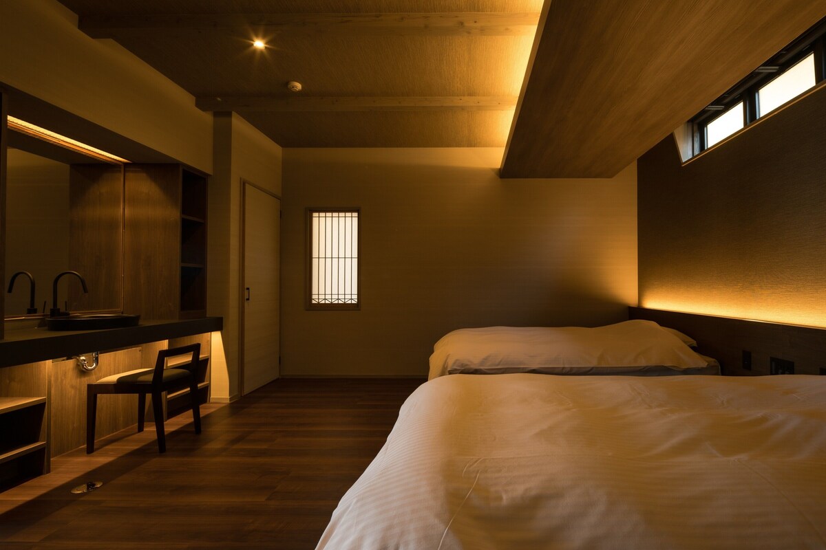 Een slaapkamer met een bed, een bureau met spiegel en een raam met tralies.
