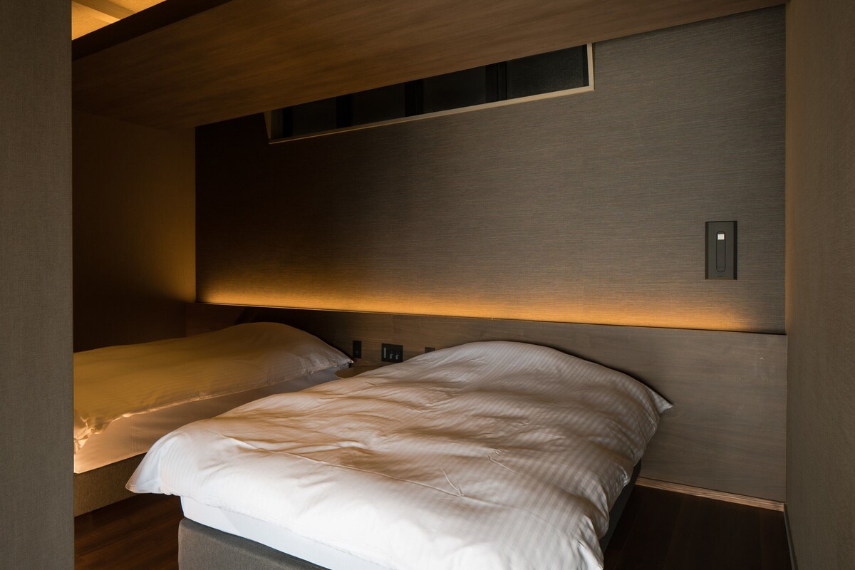 Een slaapkamer met twee bedden, een houten hoofdeinde en een klein raam.