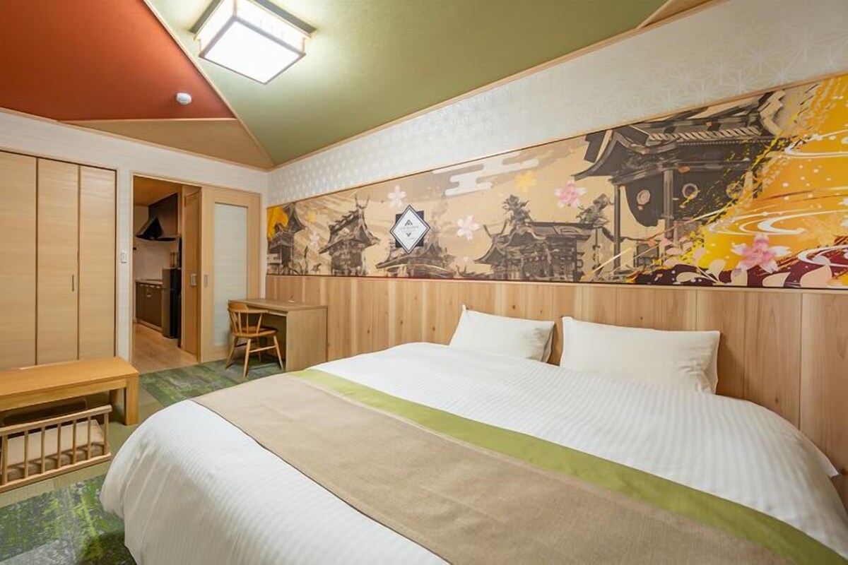 Een hotelkamer met een bed, een bureau en een stoel. Er is een kledingkast en een bankje.