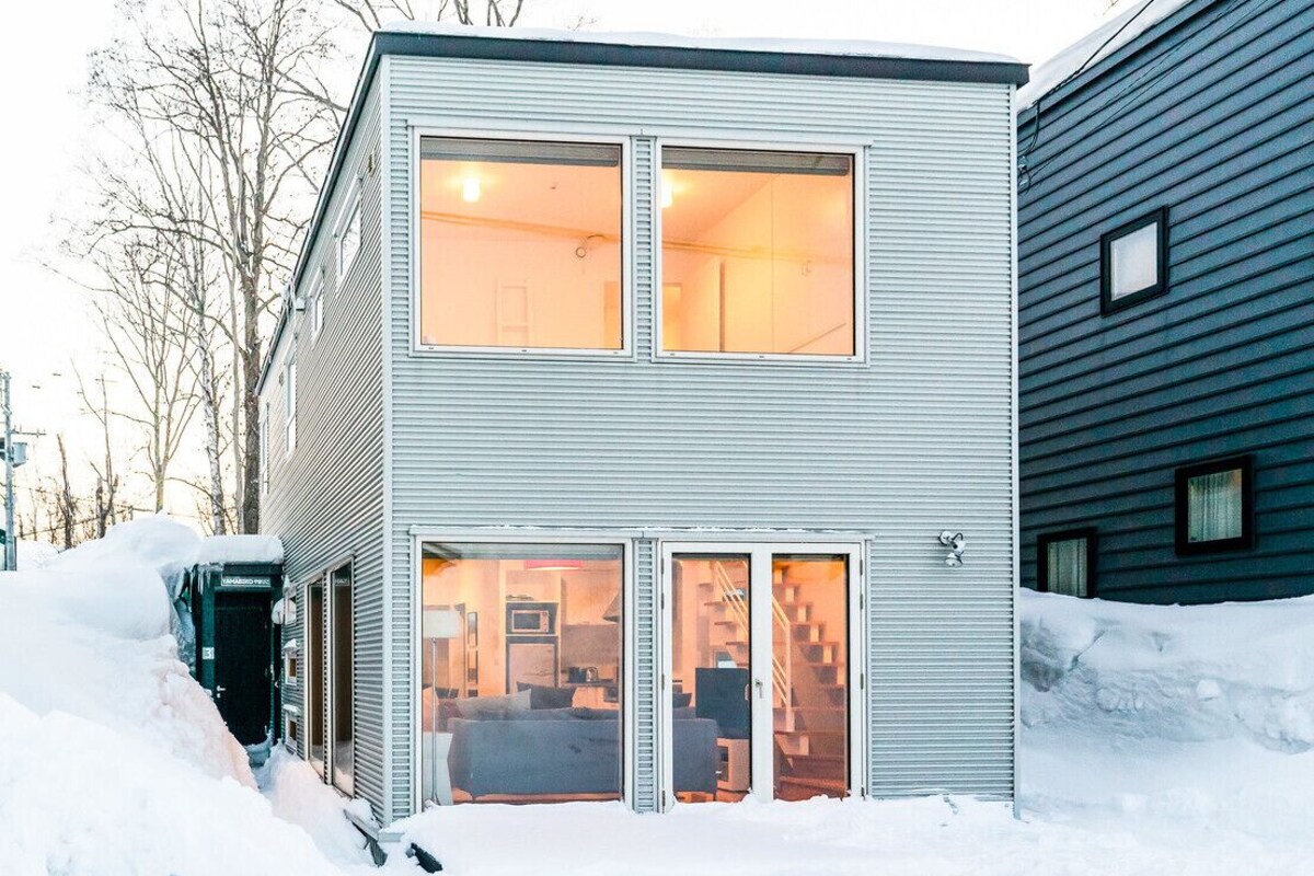 A two-story building with a garage door, a staircase leading to the upper floor, and a visible living area with furniture.