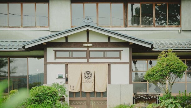 A traditional Japanese building with a tiled roof, large windows, and a small garden with a tree and a bench. - The Lake Kawaguchiko Kurashi (Fujikawaguchiko)