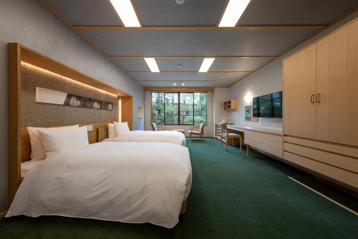 Quarto de hotel com uma cama grande, uma escrivaninha, uma televisão e um guarda-roupa.