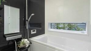 A modern bathroom with a bathtub, a shower, a window, and a mirror. - Activity Base Hida-takayama (Takayama)