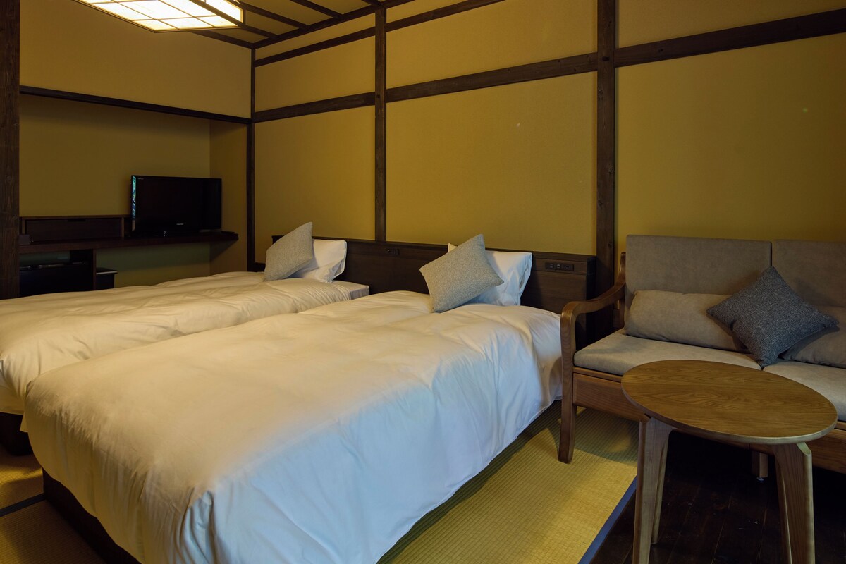 Een hotelkamer met twee bedden, een bank, een kleintje tafel en een televisie.