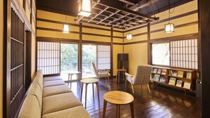 A traditional Japanese-style room with tatami mats, wooden beams, sliding doors, and a bookshelf.