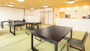 Une salle de conférence équipée de tables et de chaises, un comptoir d’accueil et des portes coulissantes traditionnelles.