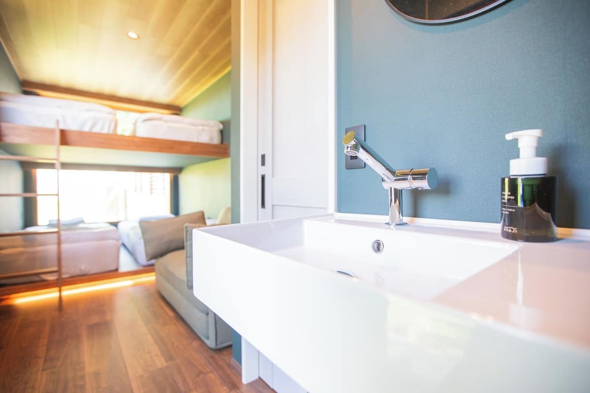 A modern bathroom with a large white sink, a mirror, and a showerhead.