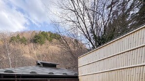 A small outdoor pond with rocks, a wooden structure, and a building with a beige exterior. - +riverpool Glamping Saitama Chichibu (Minano)
