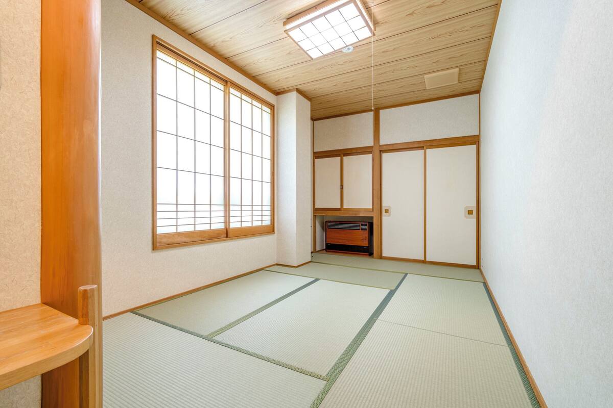 Una habitación japonesa tradicional con suelo de tatami, puertas correderas y calefacción integrada.