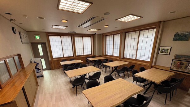 A conference room with multiple tables and chairs, large windows, and a reception desk. - +riverpool Glamping Saitama Chichibu (Minano)