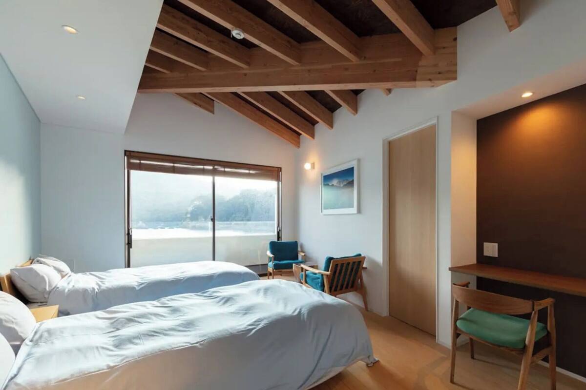 A bedroom with two beds, a desk, and a chair.