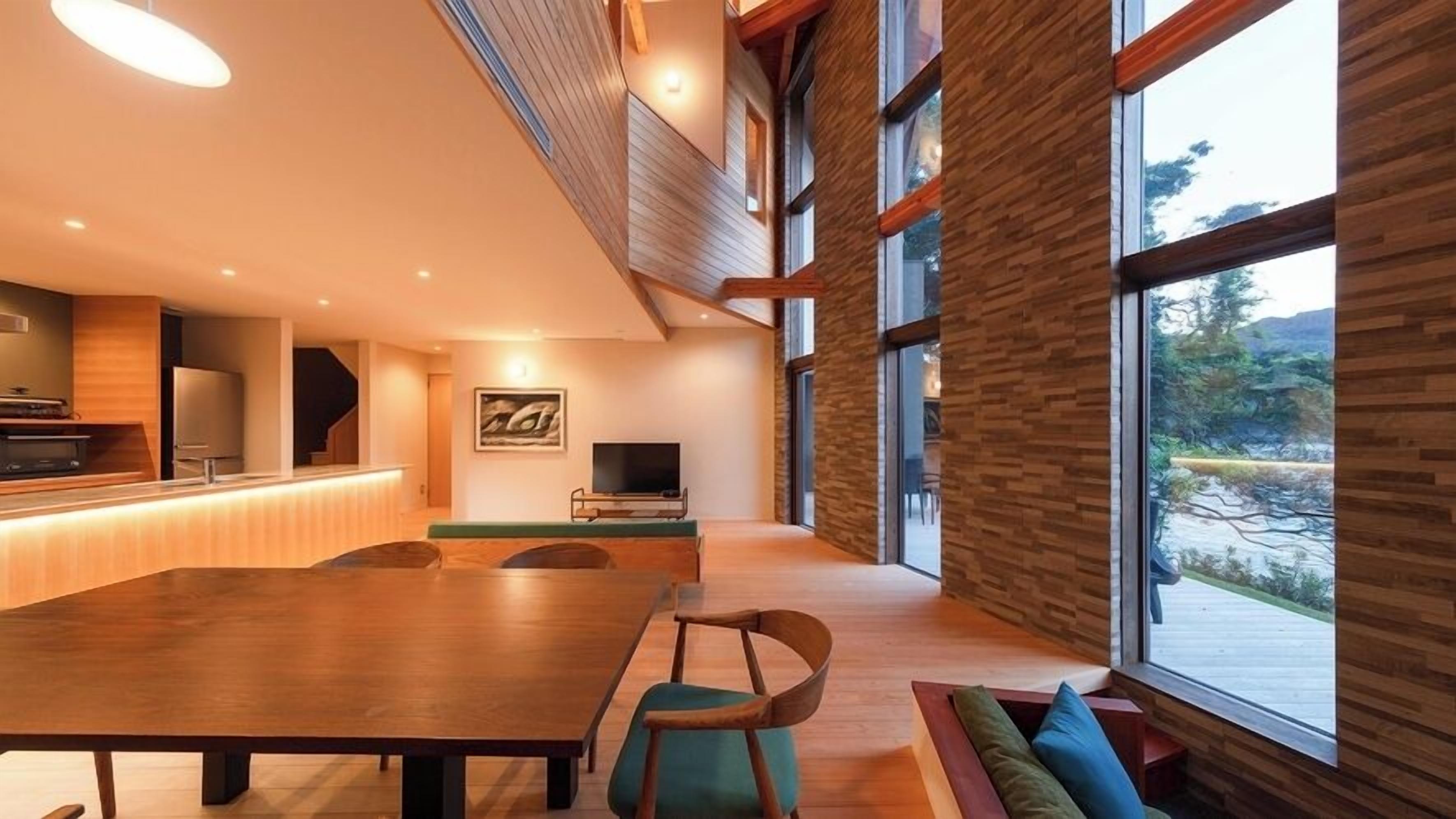 A spacious dining area with a long wooden table, chairs, and a television.