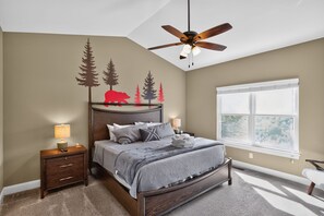 A bedroom with a bed, nightstands, a ceiling fan, a window, and a wall with tree and animal decals. - Blue Ridge Retreat | Hot Tub, Game Room & Views (Fairview)