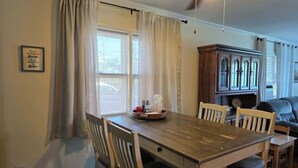 Un coin repas comprenant une table en bois, des chaises, un ventilateur de plafond et un meuble.