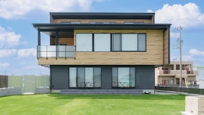 A modern two-story building with a balcony, large windows, and a flat roof.