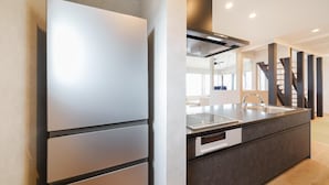 A modern kitchen with a built-in refrigerator, a stainless steel sink, and a dark countertop.