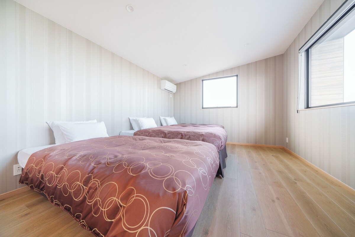Een slaapkamer met twee bedden, een raam en een houten vloer.
