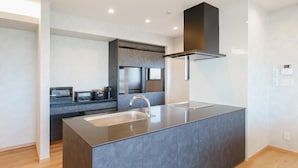 A modern kitchen with a central island, stainless steel appliances, and a sleek black range hood.
