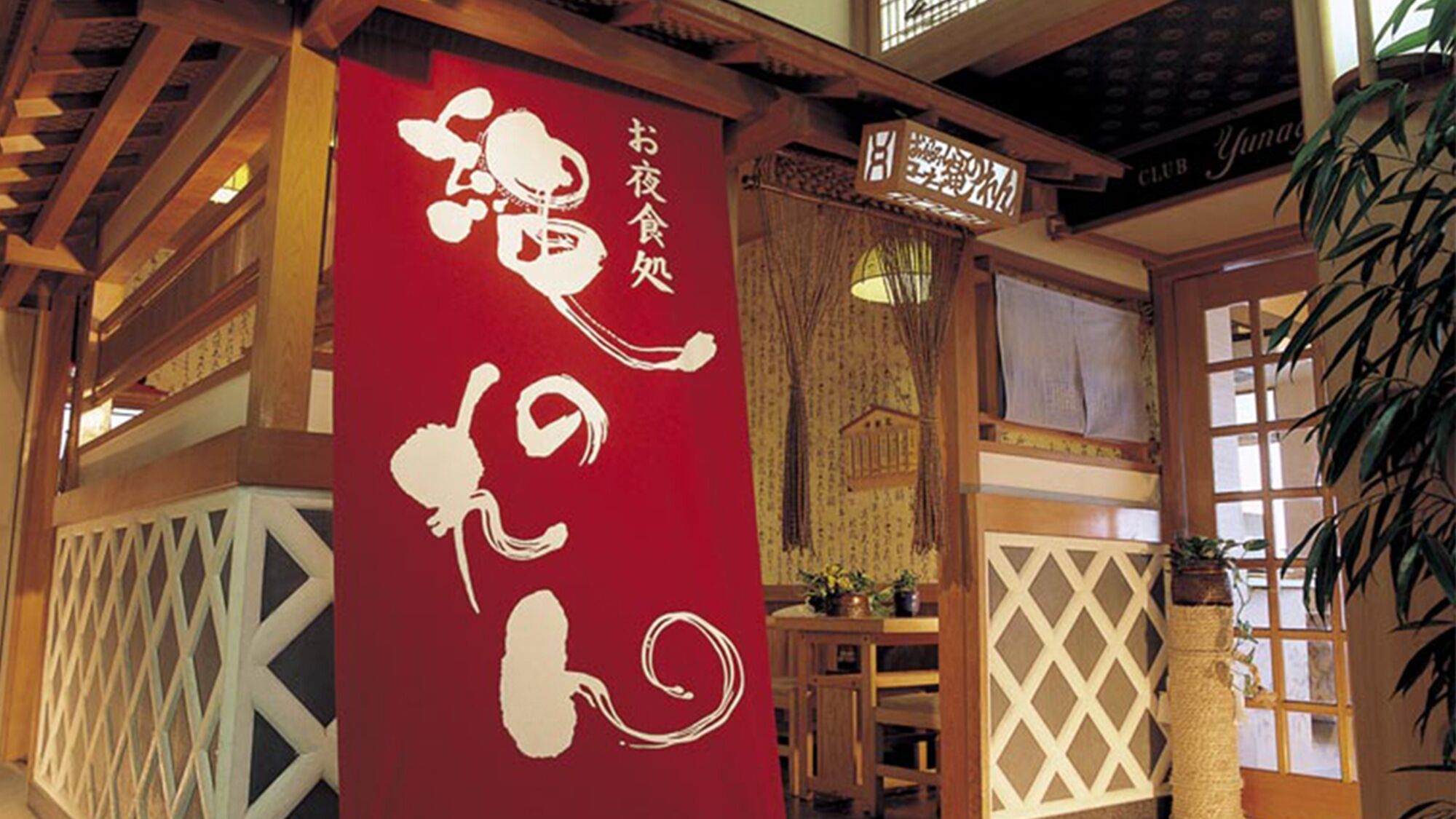 A traditional Japanese building with wooden beams, a red banner with white calligraphy, and a sign indicating a restaurant.