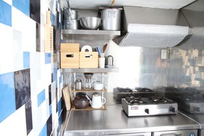 A kitchen with stainless steel appliances, a tiled backsplash, and wooden storage boxes. - Izu Cliff House (Minamiizu)
