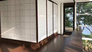 Una habitación moderna con un gran ventanal corredera, suelo de madera y vistas a una masa de agua.