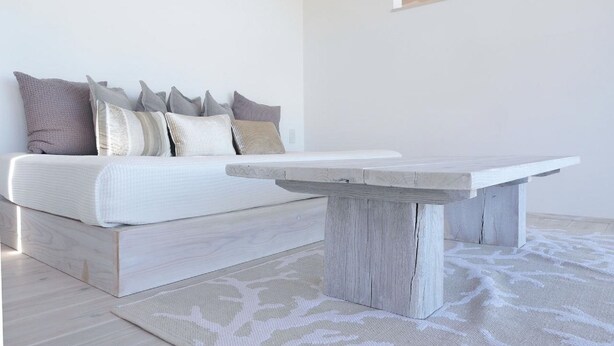 Un dormitorio minimalista con una cama, una mesita de madera y una alfombra estampada.