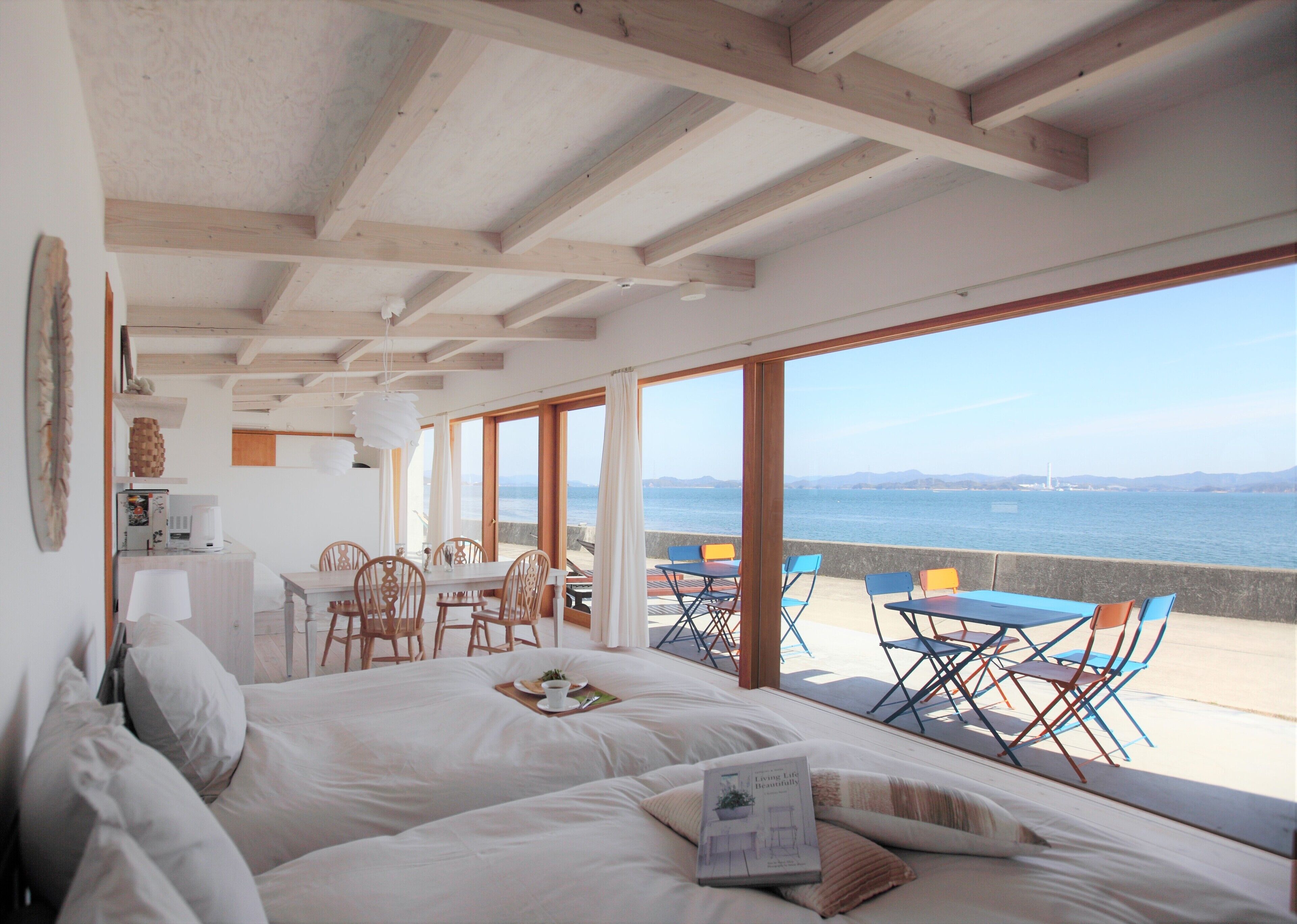 Quarto com uma cama grande, área de refeições com cadeiras e vista para o mar.