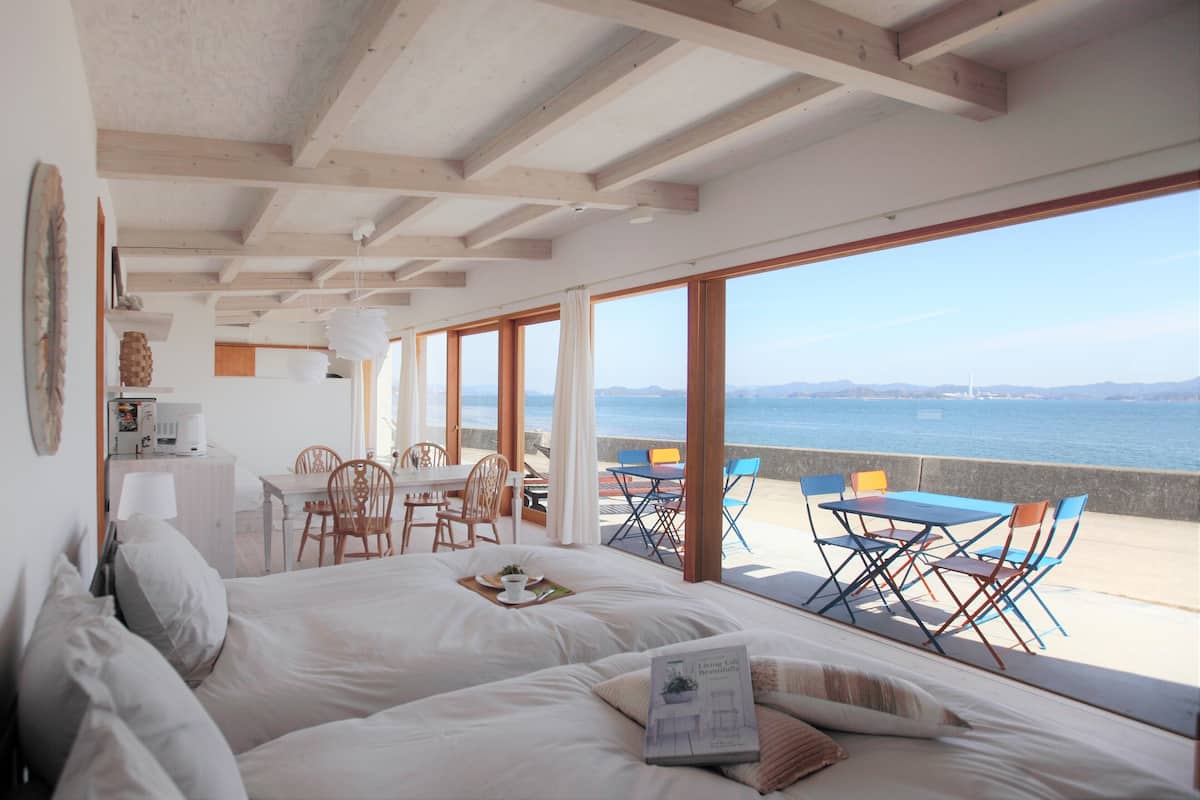 Un dormitorio con una cama grande, un comedor con sillas y vista al mar.