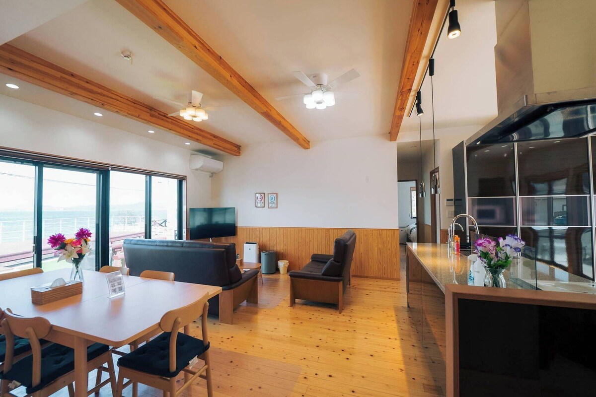 Un interior moderno con comedor, asientos, cocina y ventanas amplias.