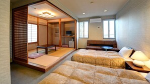 A traditional Japanese-style room with tatami flooring, a futon bed, a small television, and a sliding door. - Petit Hotel North Inn (Ito)