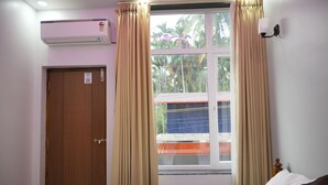 Une chambre d’hôtel comprenant un lit, des rideaux, un appareil de climatisation, une fenêtre avec vue et un luminaire fixé au mur.