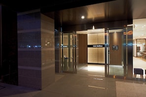 Entrada de un hotel de diseño moderno, con puerta de vidrio y un cartel que dice "Hotel SunClover".